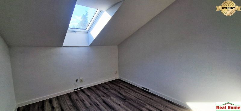 Attic room with a large skylight and wooden decor flooring in a family house.