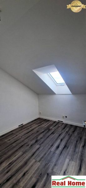 Attic room with a wooden decor floor and a skylight in a family house.