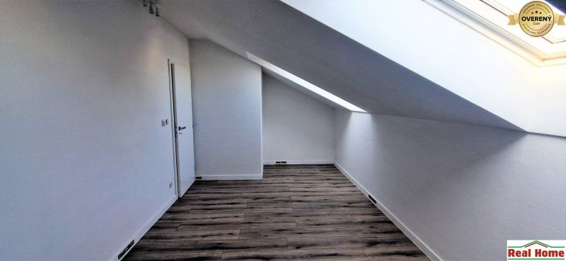 Attic in a family house with a wooden decor floor and a skylight.