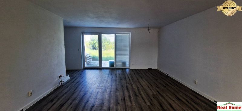 A room in a family house, large windows, white walls, wooden decor flooring.