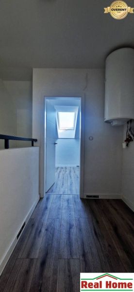 A hallway in a family house with a wooden decor floor, a skylight in the background.