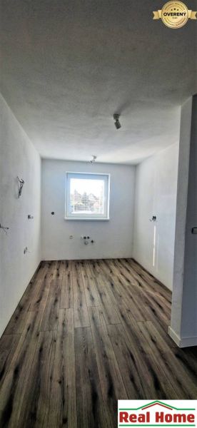 A view into a room of a family house with a wooden decor floor and a window.