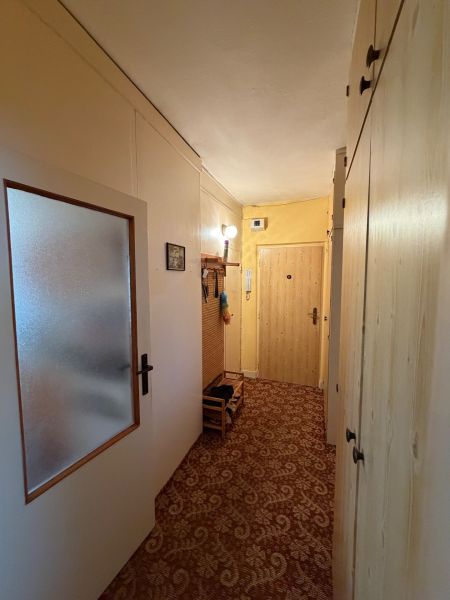 Hallway of a 2-room apartment with built-in wardrobes and carpeted floor.