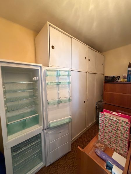 An open refrigerator and built-in wardrobes in the room of a 2-room apartment.