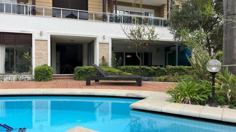 A pool with a lounger and a garden in front of a unique property in Side, Turkey.