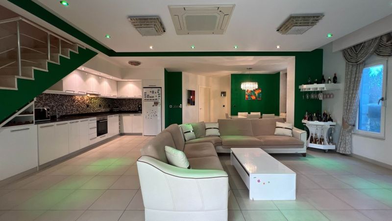 Living room with a sofa, kitchen, dining area, and white furniture in a unique property.