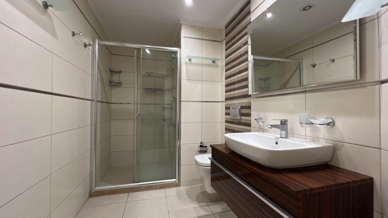 Bathroom with a shower, sink, and cabinets with a wooden decor on Unique Properties.