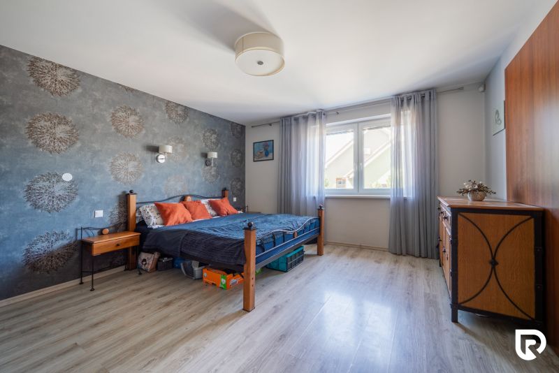 A bedroom in a family house with a wooden decor floor, wallpaper, and solid wood furniture.