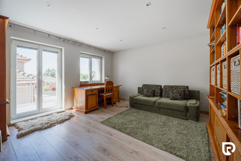 Living room in a family house with wood-patterned flooring, a sofa, and a desk.