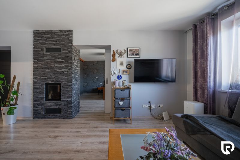 Interior of a family house with a television, decorations, and a wooden-patterned floor.