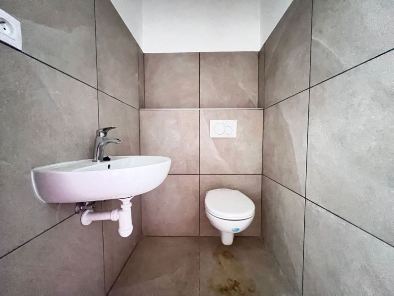 Toilet with sink, neutral tiles, commercial premises.
