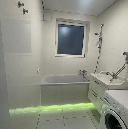 White bathroom in a 3-room apartment with a bathtub and a washing machine.