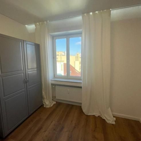 A room in a 3-room apartment with white curtains and a floor with a wooden decor.