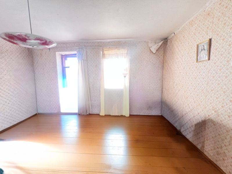 A room in a family house with a wooden decor floor, a floral chandelier, and a painting on the wall.