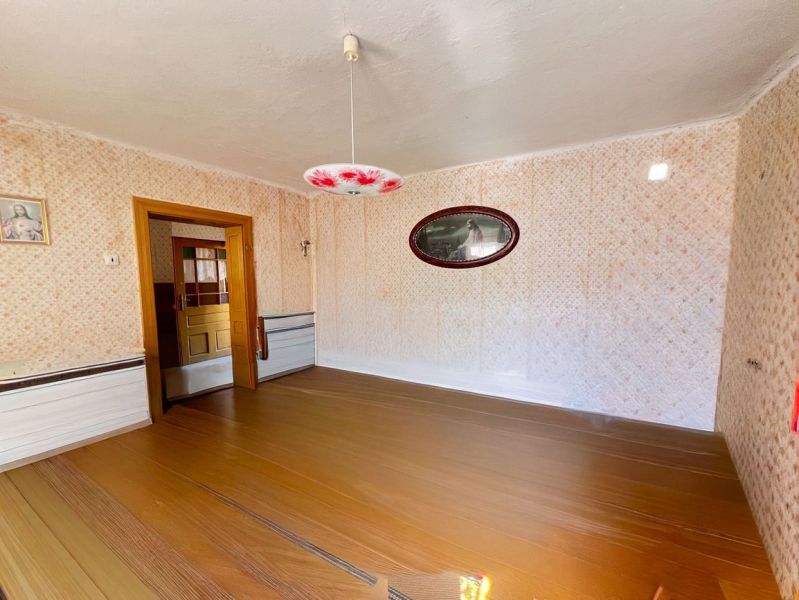 A room in a family house with a wooden decor floor and patterned walls.