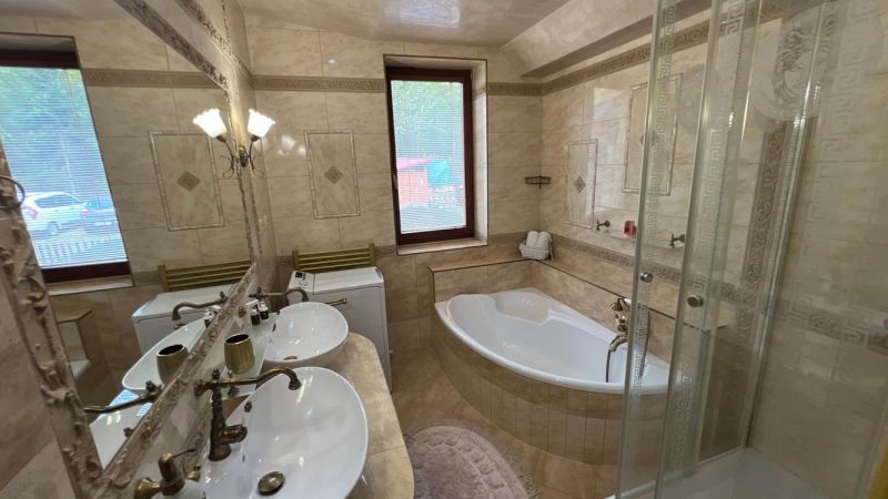 A bathroom in a villa with a bathtub, shower, and double sink.