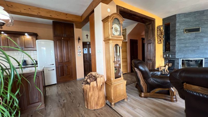 Interior of a villa with wooden decor flooring, antique clock, and fireplace.