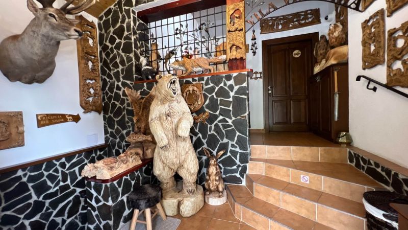 Interior of a villa with wooden animal sculptures and stone walls.