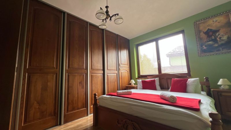 Bedroom in a villa with a large wardrobe, bed, painting, and wooden decor.