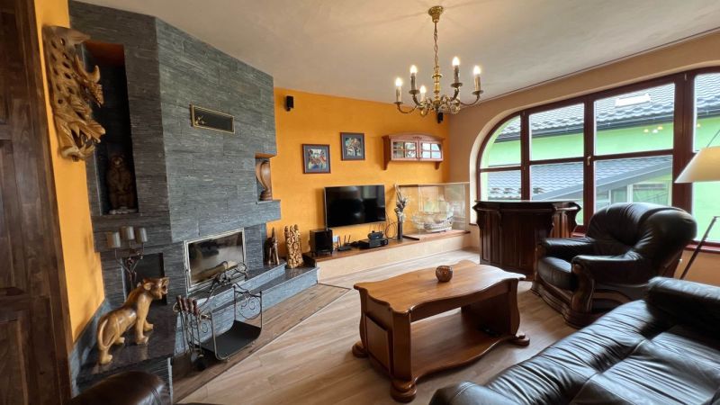 Living room in a villa with a fireplace, wooden decor flooring, and leather furniture.