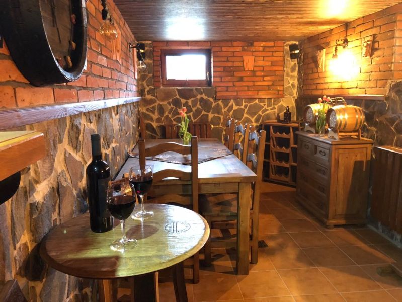 A wine cellar with brick walls and a wooden table in a villa, wine on the table.