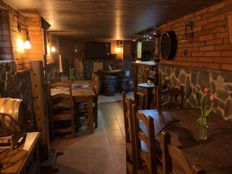 A villa with a cozy wine cellar, brick walls, barrels, and rustic wooden furniture.