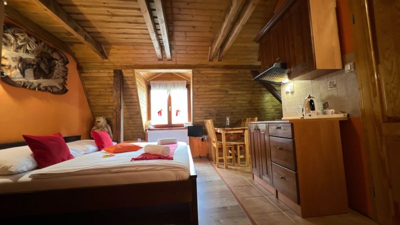 Wooden beams, bed, kitchenette, and table in the attic of the Villa.