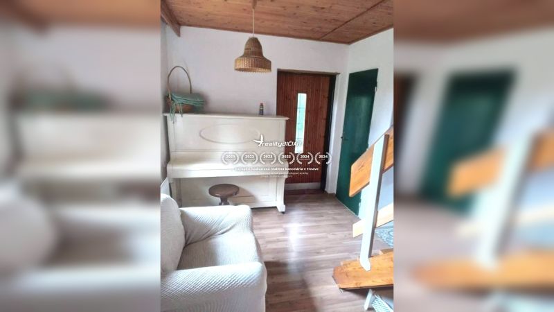 Interior of a family house with a white piano, wooden decor flooring, stairs, and wooden ceiling.