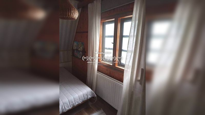 A room in a family house with dark wood paneling and a bed by the window.