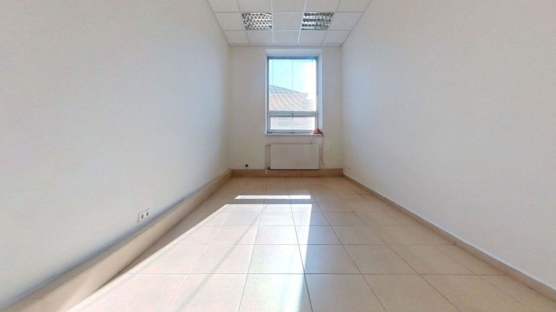 A bright office with a tiled floor and a large window letting in light.