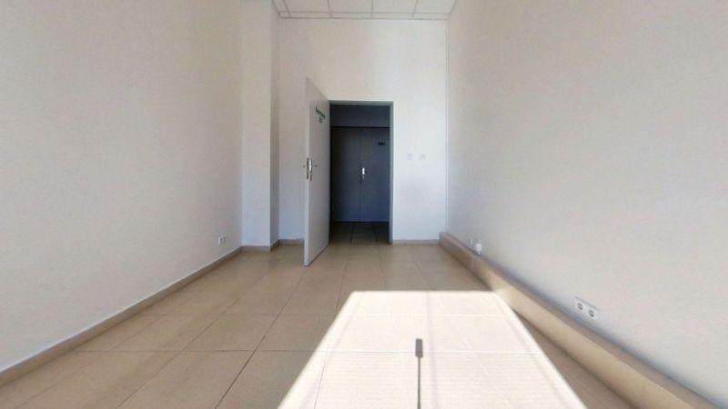 The interior of an office with white walls and light ceramic floor tiles.