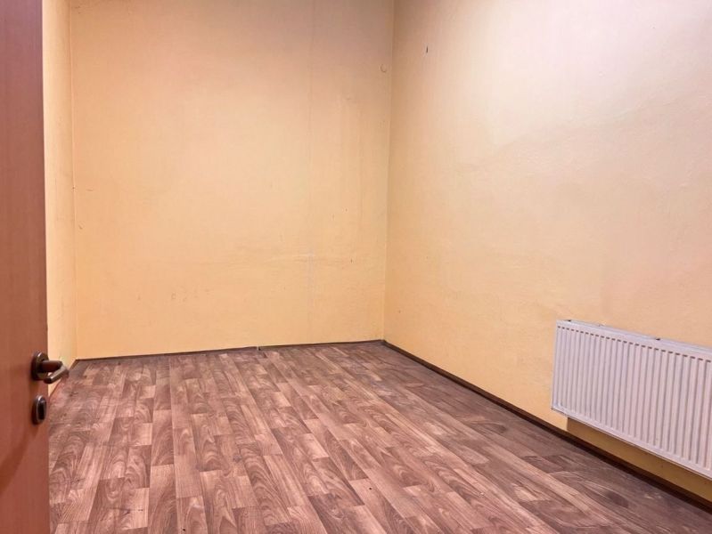 A room with a wooden decor floor, yellow walls, and a radiator in warehouses and halls.