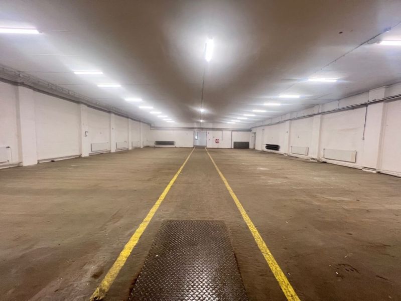 A wide warehouse interior with lighting and marked flooring in the space of warehouses and halls.