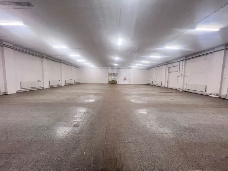 Spacious interior of warehouses and halls with ceiling lighting and tiled flooring.