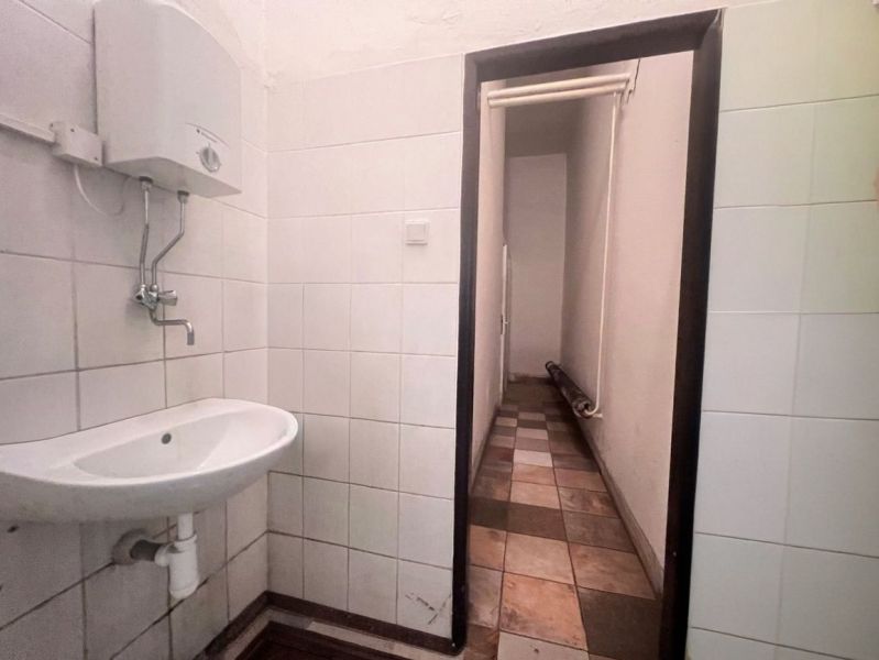 Interior of a bathroom in warehouses and halls with a sink and a wall-mounted water heater.
