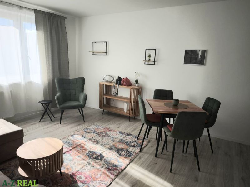 Living room in a two-room apartment with a green armchair and wooden floor decor.