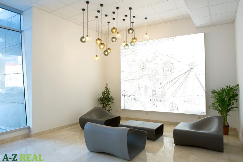 Offices with modern seating, pendant lights, and a decorative wall panel.