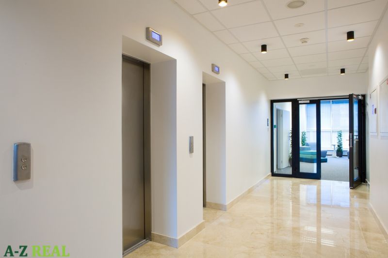 In the offices, you can see a hallway with elevators and light marble flooring.