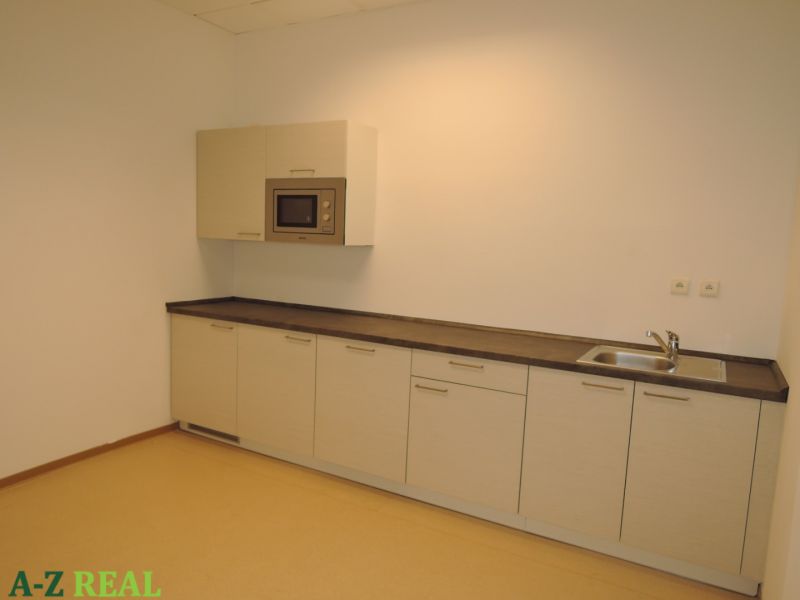 A kitchen unit with a built-in microwave and sink in the office.