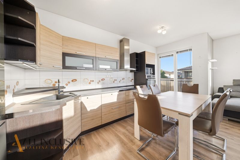 A kitchen in a 3-room apartment with a wooden decor floor and a dining table.
