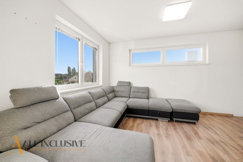 A bright living room with a corner sofa and a wooden decor floor in a 3-room apartment.