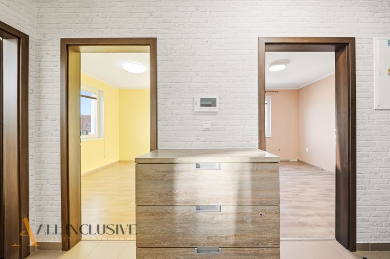 A bright interior of a 3-room apartment with a wooden decor floor and brick cladding.
