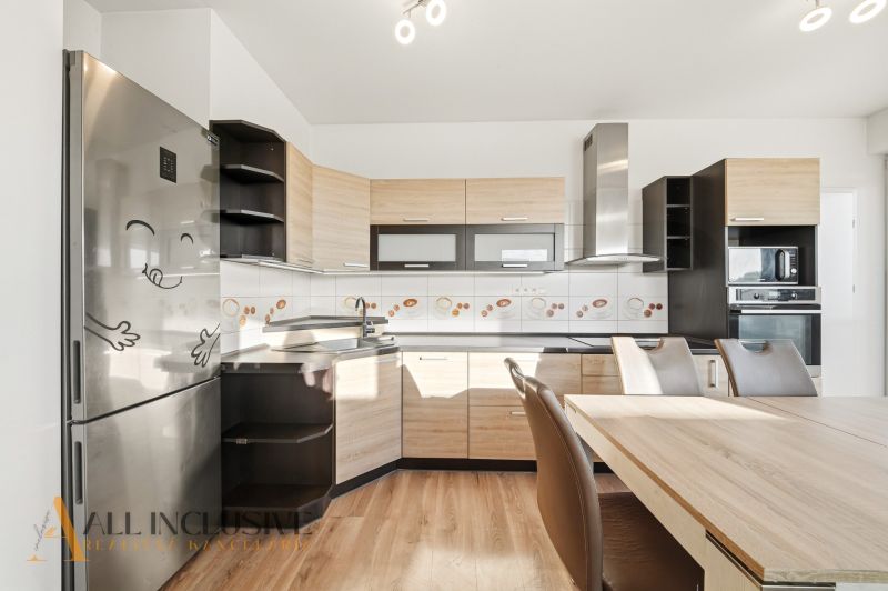 A kitchen in a 3-room apartment with a wooden decor floor and light furniture.
