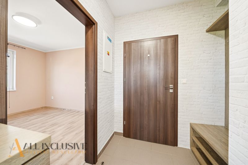 Entrance hall in a 3-room apartment with white walls and wooden doors.