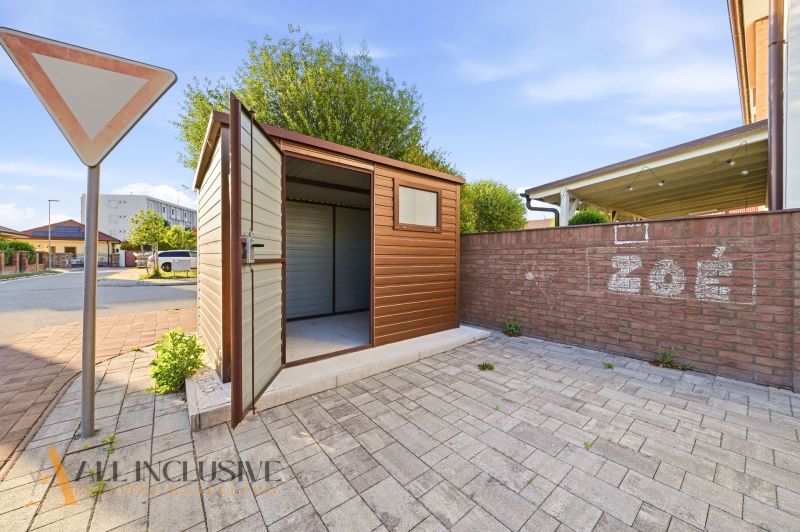 A shed with open doors next to a brick fence in Dunajská Streda.