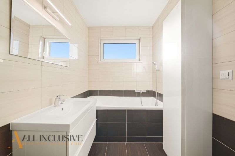 Bathroom in a 3-room apartment with a bathtub, sink, and light tiles.