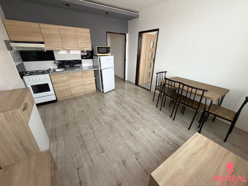A kitchen with wooden decor and a dining table in a studio apartment.