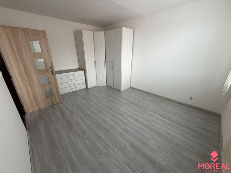 A room in a one-room apartment with a wooden decor floor and a built-in wardrobe.