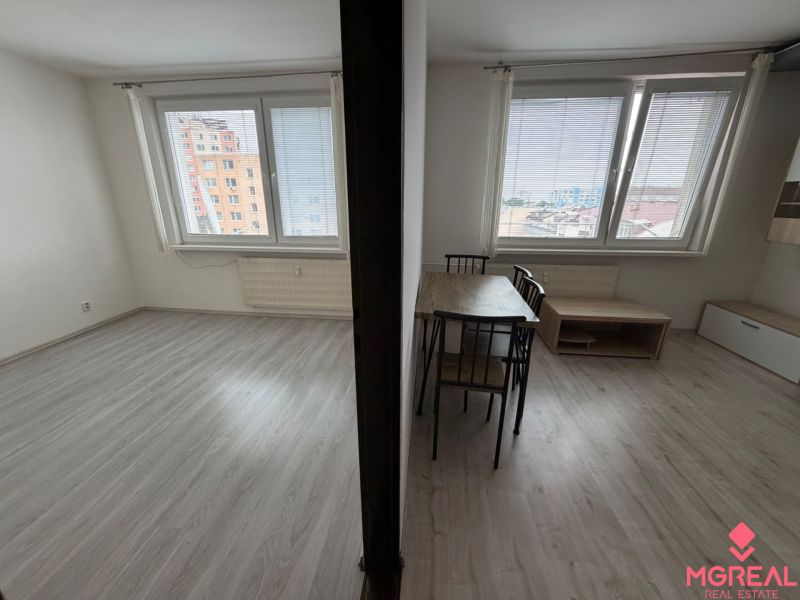 Interior of a one-room apartment with a wooden decor floor and a table.