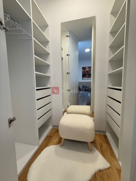 Family house with a wardrobe, wooden decor flooring, and a comfortable chair.